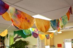 colorful paper streamers hanging from the ceiling in an art room with potted plants