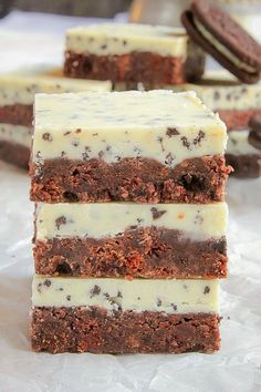 four pieces of chocolate cake with white frosting and oreo cookies in the background