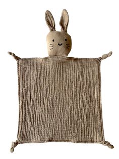 a stuffed rabbit is sitting on top of a blanket that's made out of fabric