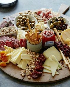 an assortment of cheeses and meats on a wooden platter