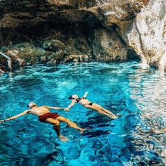 two people are swimming in the blue water