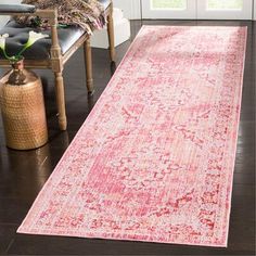 a large pink rug in the middle of a room with a chair and window behind it