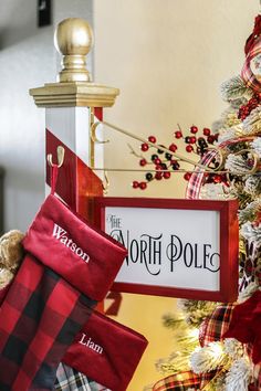 the north pole christmas tree is decorated with red and black plaid stockings