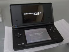 a nintendo ds game system sitting on top of a white tablecloth covered napkins