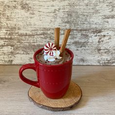 a red cup filled with hot chocolate and marshmallows on top of a wooden coaster