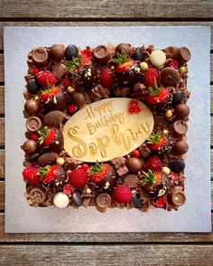 a birthday cake decorated with strawberries and chocolates