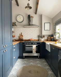 a kitchen with blue cabinets and an oven in the center, along with a rug on the floor