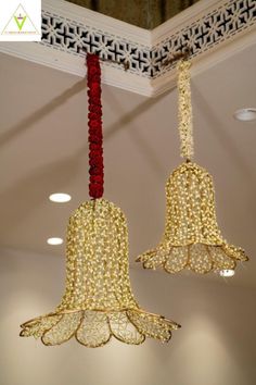 two red and gold bells hanging from the ceiling in a room with white wallpaper