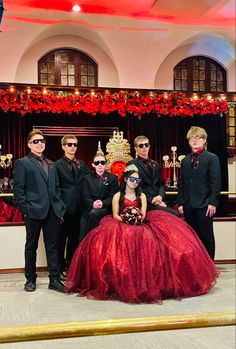 a group of people standing next to each other in front of a red and gold dress