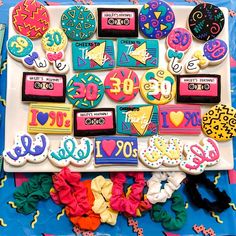 decorated cookies are arranged on top of a blue tablecloth with colorful decorations and letters