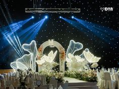 a stage set up for a wedding with white flowers and angel wings in the center