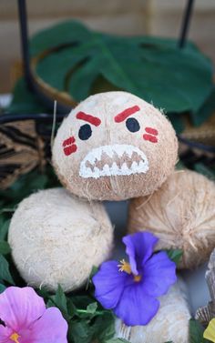 a stuffed animal sitting on top of a table next to some purple flowers and green leaves