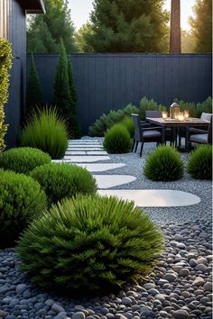 an outdoor dining area with gravel, rocks and plants in the foreground is lit by candles