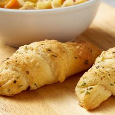 two croissants on a cutting board next to a bowl of macaroni and cheese