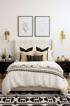 a white bed with black and gold pillows on top of it next to two framed pictures