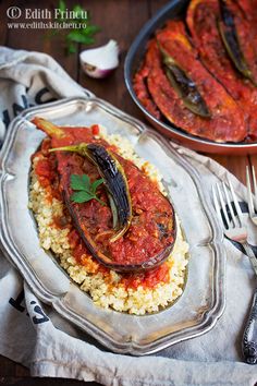 an eggplant dish with red sauce and rice on a plate next to another dish