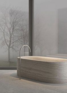 a bath tub sitting in front of a window next to a large glass wall with trees outside