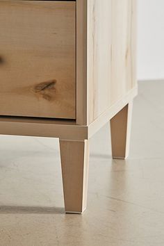 a close up of a wooden drawer on a floor with a white wall in the background