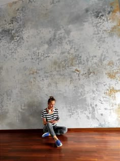 a young boy sitting on the floor using his cell phone while looking at something in front of him