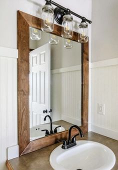 a bathroom with a sink, mirror and two lights on the wall above it's vanity