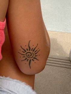 a woman with a sun tattoo on her arm and leg, sitting down next to a shoe