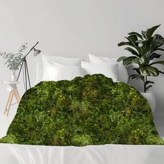 a bed covered in green moss next to a potted plant