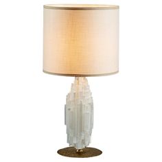 a table lamp with a white shade on the base and a beige drum light behind it