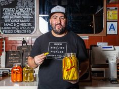 a man holding two jars filled with pickles