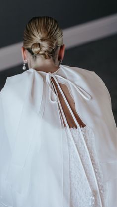 the back of a woman's dress with a white cape on her shoulders and long hair in a bun