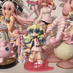 some anime figurines are sitting on a table with one doll in the foreground