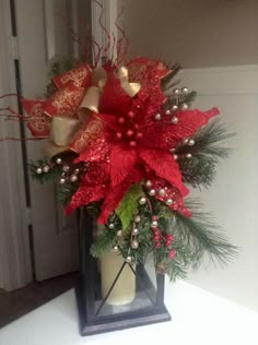 a red and gold poinsettia arrangement in a lantern holder on a table