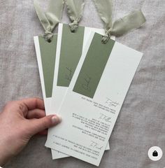 the person is holding up two cards with ribbons on them, which are attached to each other