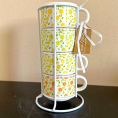 a stack of four cups sitting on top of a table next to a tag with flowers