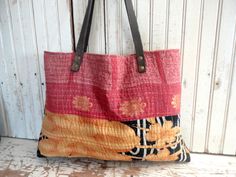 an orange and black bag hanging on a white wooden wall next to a brown leather handle