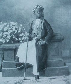 an old black and white photo of a woman sitting on a bench with a cane