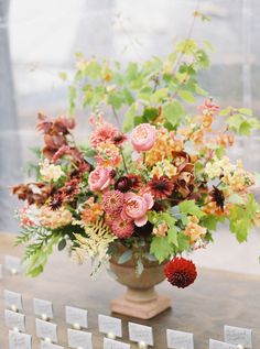 a vase filled with lots of flowers sitting on top of a table next to cards