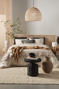 a large bed sitting in a bedroom next to a table with two vases on it