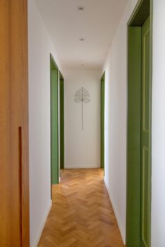 an empty hallway with green doors and white walls