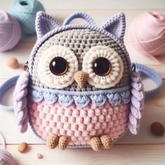 a crocheted owl purse sitting on top of a wooden table next to balls of yarn