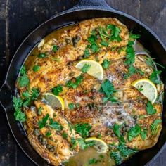 a skillet filled with chicken covered in lemons and herbs