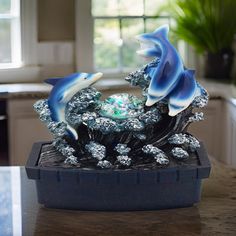 two dolphins in a bowl on top of a kitchen counter next to a potted plant