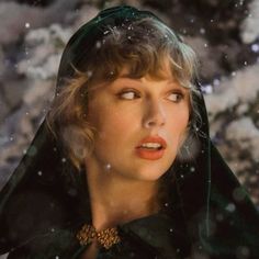 a woman wearing a green cloak in front of snow covered rocks with her mouth open