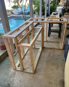 several pieces of wood sitting on top of a floor next to a swimming pool in a backyard