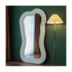 a lamp is next to a large mirror on the wall in a room with green walls