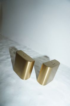 two gold square shaped objects sitting on top of a bed