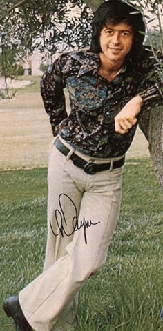 an old photo of a man in the grass holding a baseball bat and posing for a picture