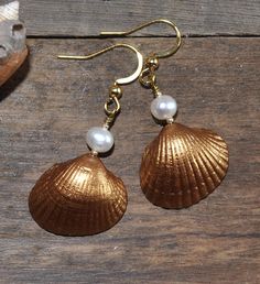 "Stylish earrings with beautiful gold painted seashells and white freshwater pearls. 18K gold plated nickel-, lead- and cadmium-free stainless steel hooks. Measure about 30mm (1,2\") from the lower part of the hook. These earrings will come in a pretty organza gift bag ready for gifting! If you have any questions just convo me and I will get back to you as soon as possible. Thanks for looking // Mari" Shell-shaped Pearl Earrings For Gift, Summer Gold Nickel-free Jewelry, Gold Shell Dangle Earrings, Elegant Shell Dangle Jewelry, Pearl White Shell-shaped Jewelry With Pearl Drop, Shell-shaped Gold Jewelry For Wedding, Elegant Gold Pearl Earrings For Summer, Gold Ocean-inspired Beach Earrings, Gold Dangle Shell Earrings For Summer