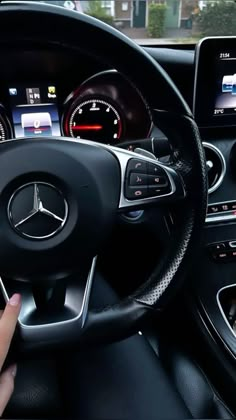 a person driving a car with their hand on the steering wheel and dashboard screen showing