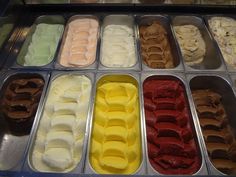 an assortment of ice creams in trays with different colors and flavors on display