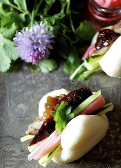 two small sandwiches are sitting on a glass plate next to some flowers and other items